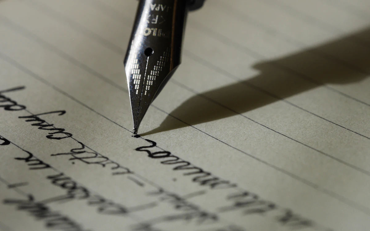 Hand writing a personal letter with a pen, representing major donor direct mail